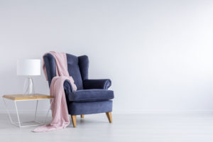 Blue chair with pink blanket on it against white wall Interior Design Ellecor