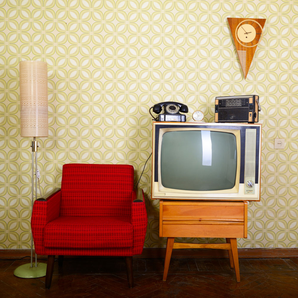 Red chair and a retro tv in front of a 1970s wallpaper