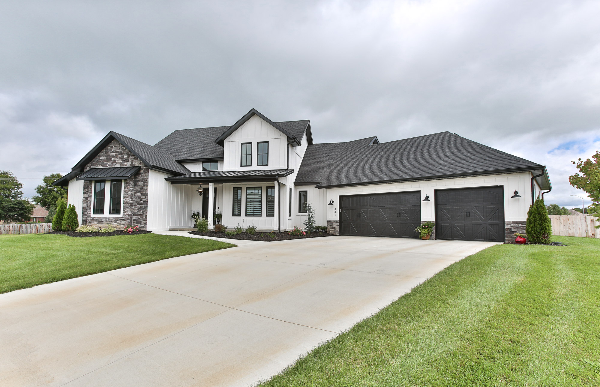 Front view by driveway two-story house green grass three-car garage abby-farm-house-2