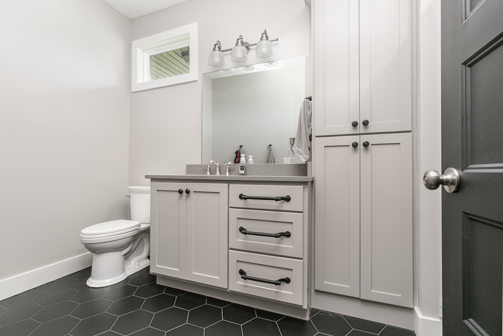 Bathroom showing toilet, single vanity, and towel closet with hexagonal tiles on floor abby-farm-house-21