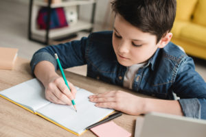 Boy sitting at desk at home with pencil writing Ellecor Home Design