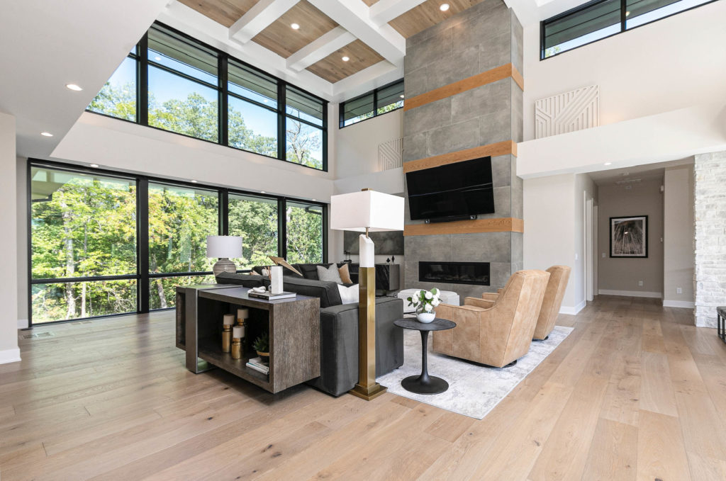 A modern living room with high ceilings, wood floors, and contemporary furniture.